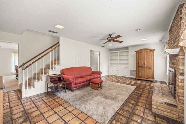 living room with a fireplace, a textured ceiling, built in shelves, and ceiling fan