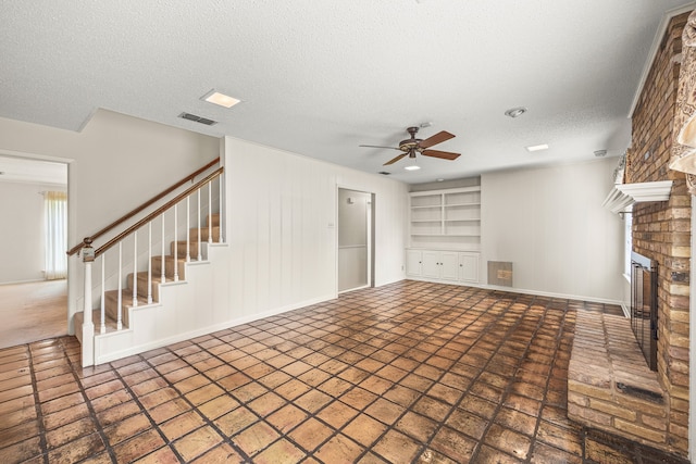 unfurnished living room with a textured ceiling, a brick fireplace, built in features, and ceiling fan