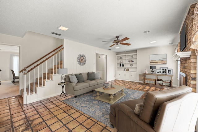 living room featuring a textured ceiling, ceiling fan, built in shelves, and a fireplace