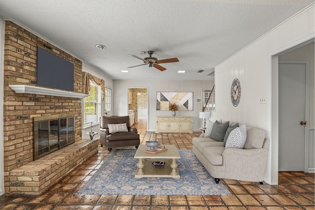 living room featuring a fireplace, a textured ceiling, and ceiling fan