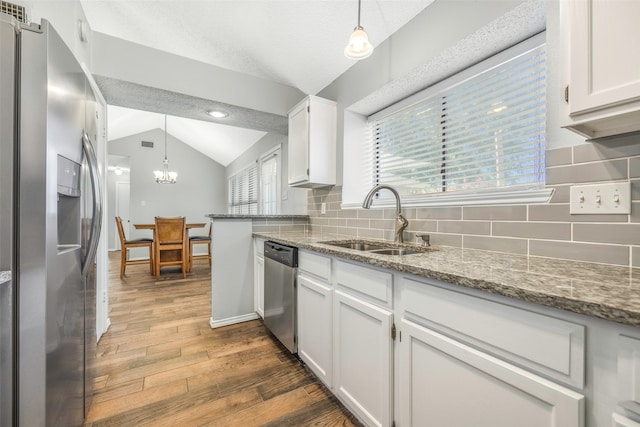 kitchen with backsplash, white cabinets, sink, vaulted ceiling, and stainless steel appliances