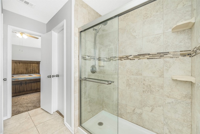 bathroom with ceiling fan, a shower with shower door, and a textured ceiling