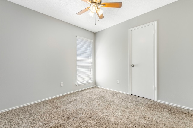 empty room with carpet flooring, ceiling fan, and a textured ceiling