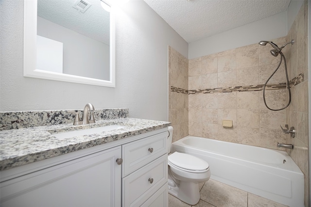 full bathroom featuring tiled shower / bath combo, tile patterned flooring, a textured ceiling, toilet, and vanity