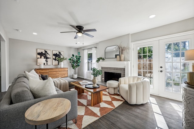 living room featuring french doors, a healthy amount of sunlight, a brick fireplace, and dark hardwood / wood-style flooring