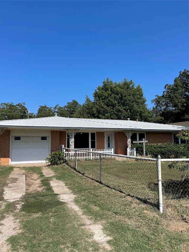 single story home with covered porch, a garage, and a front lawn