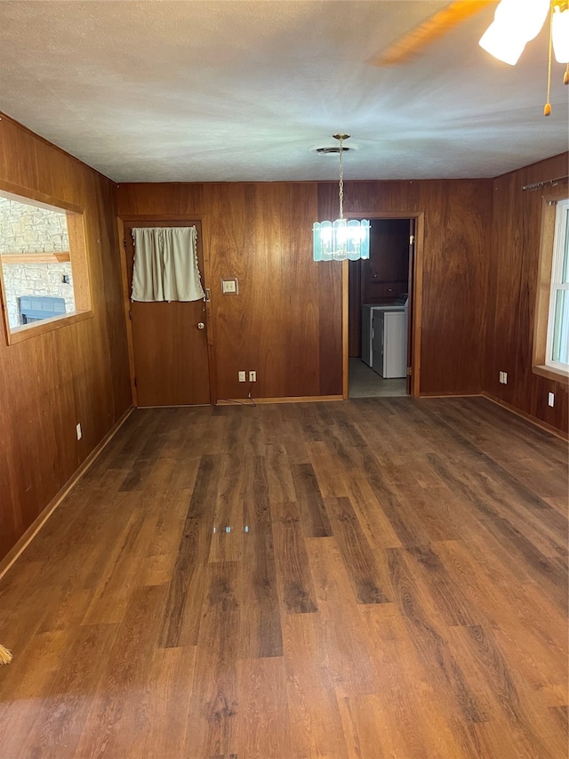 spare room featuring washer / dryer, wood walls, and dark hardwood / wood-style flooring