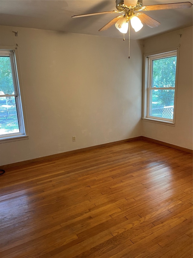 empty room featuring a wealth of natural light, ceiling fan, and light hardwood / wood-style floors