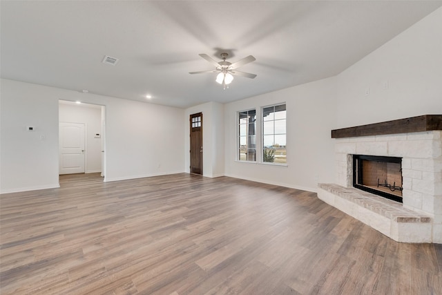 unfurnished living room with ceiling fan, a fireplace, and light wood-type flooring