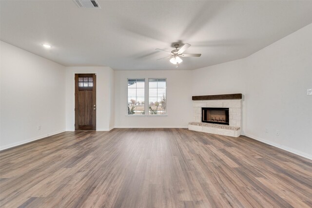 unfurnished living room with a stone fireplace, ceiling fan, and hardwood / wood-style flooring