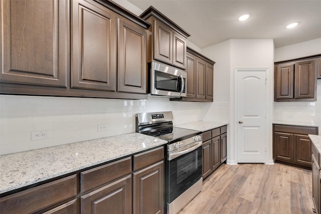 kitchen with light stone counters, light hardwood / wood-style flooring, backsplash, dark brown cabinets, and appliances with stainless steel finishes