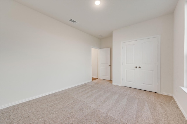 unfurnished bedroom with light carpet and a closet