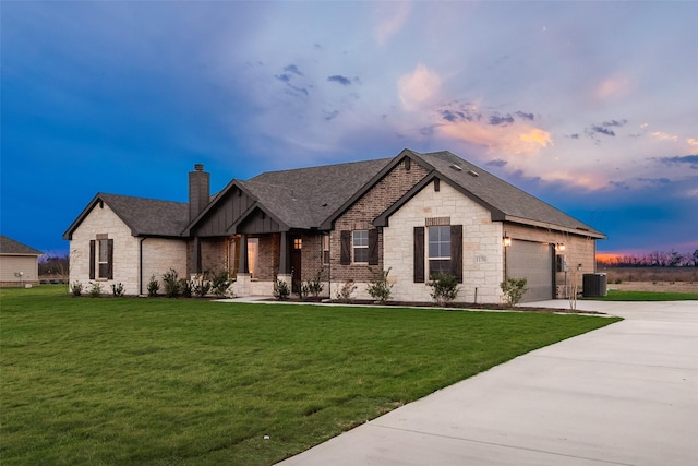 view of front of home with a lawn, cooling unit, and a garage