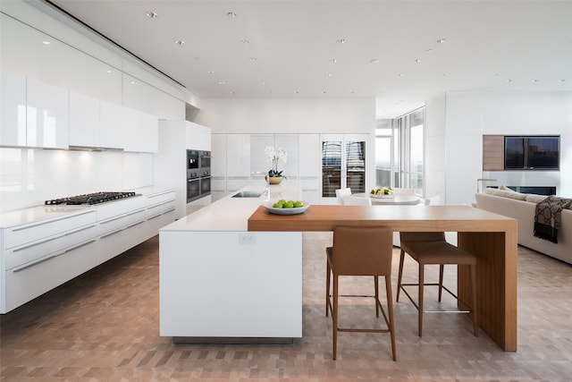 kitchen with white cabinetry, a kitchen island, sink, a breakfast bar, and appliances with stainless steel finishes