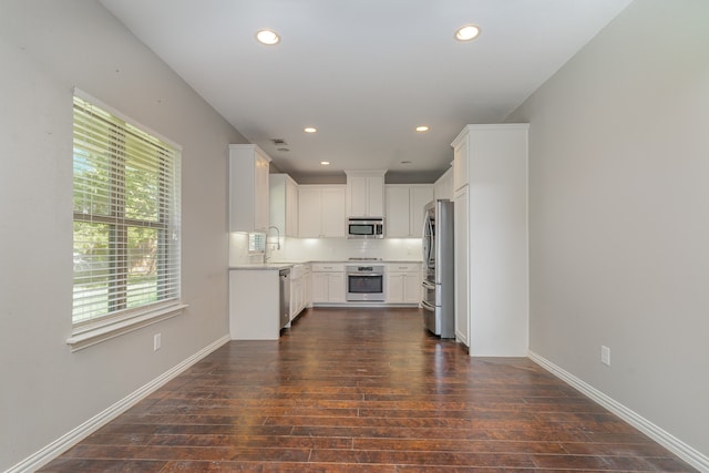 kitchen with appliances with stainless steel finishes, sink, white cabinets, dark wood-type flooring, and decorative backsplash