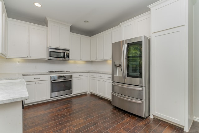 kitchen with backsplash, appliances with stainless steel finishes, dark hardwood / wood-style floors, and white cabinets