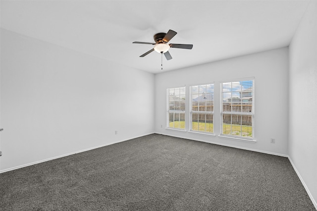 spare room featuring ceiling fan and dark colored carpet