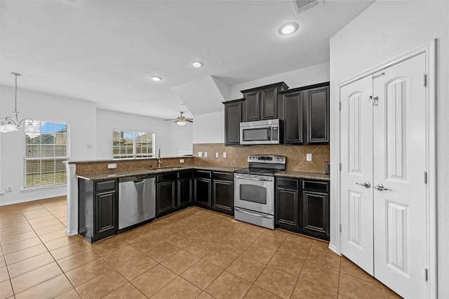 kitchen with ceiling fan with notable chandelier, decorative light fixtures, appliances with stainless steel finishes, tasteful backsplash, and light tile patterned flooring