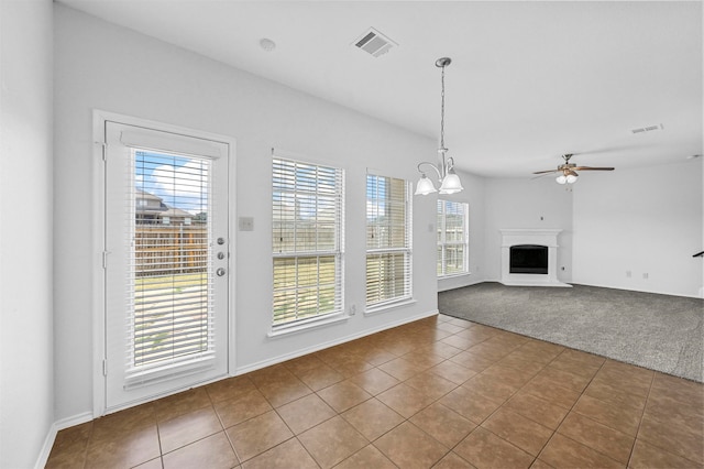 unfurnished living room featuring ceiling fan with notable chandelier and tile patterned flooring