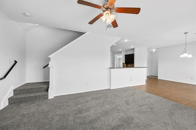 unfurnished living room with ceiling fan with notable chandelier and dark colored carpet