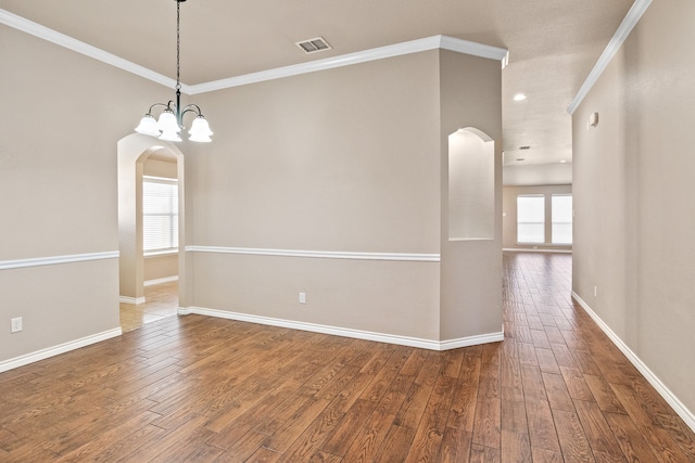 unfurnished room with ornamental molding, hardwood / wood-style floors, and an inviting chandelier