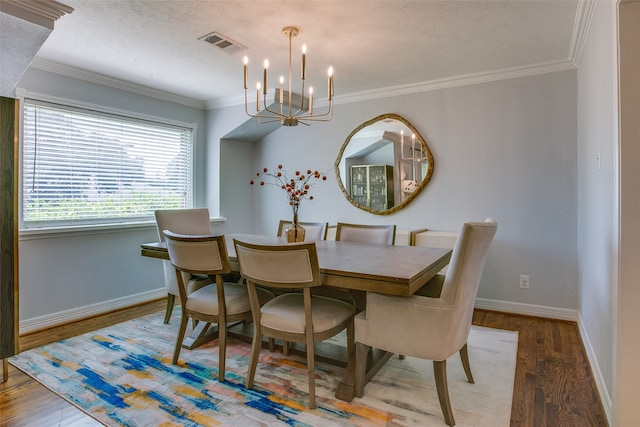 dining area with ornamental molding, a textured ceiling, hardwood / wood-style floors, and an inviting chandelier