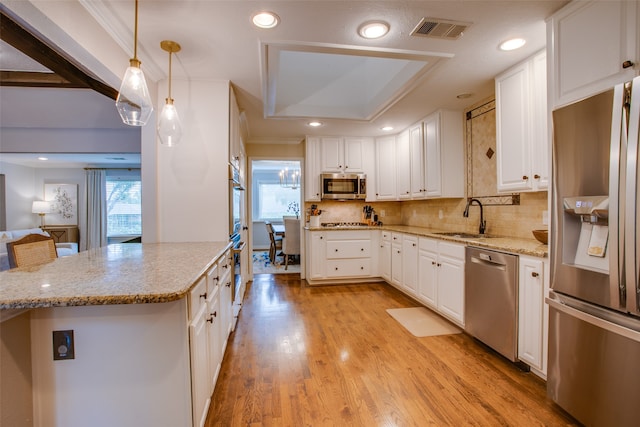 kitchen featuring light hardwood / wood-style flooring, appliances with stainless steel finishes, hanging light fixtures, sink, and white cabinetry