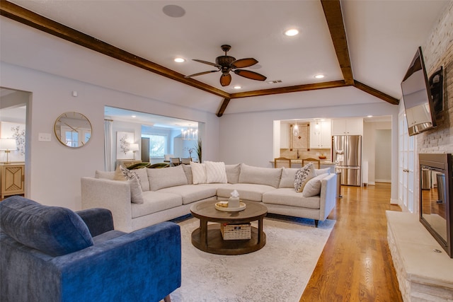 living room featuring lofted ceiling with beams, light hardwood / wood-style flooring, ceiling fan, and a large fireplace