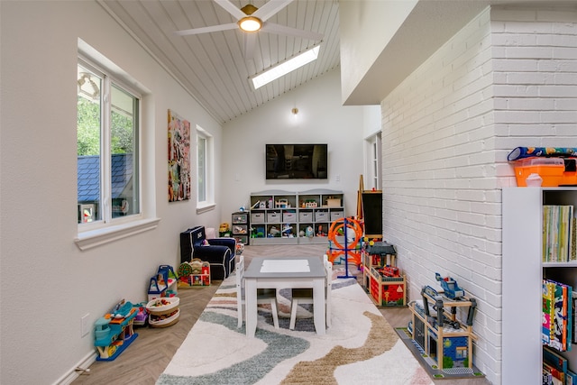 playroom featuring parquet flooring, lofted ceiling with skylight, and ceiling fan