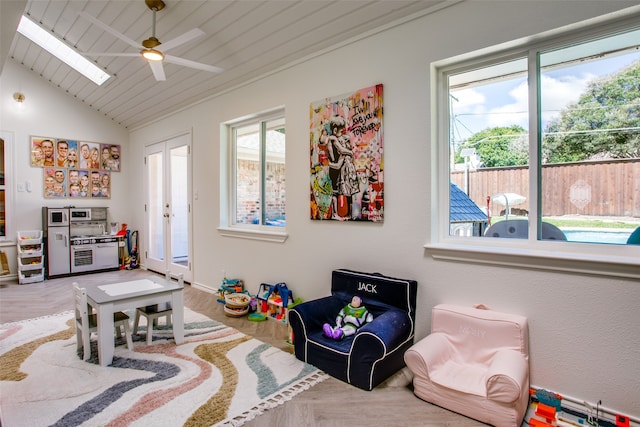 recreation room featuring hardwood / wood-style floors, lofted ceiling with skylight, ceiling fan, wooden ceiling, and french doors