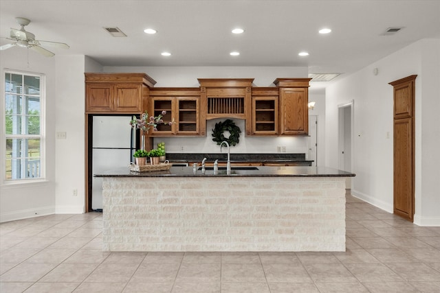 kitchen featuring a kitchen island with sink, sink, ceiling fan, white refrigerator, and light tile patterned flooring