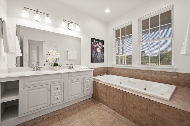 bathroom featuring tile patterned flooring, tiled bath, and vanity