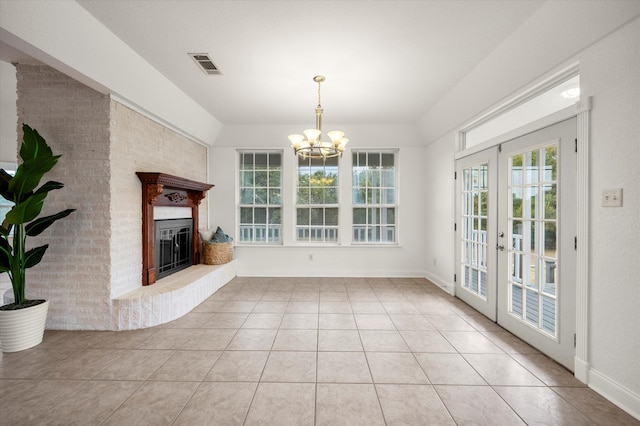 unfurnished living room featuring a fireplace, french doors, light tile patterned flooring, and a notable chandelier