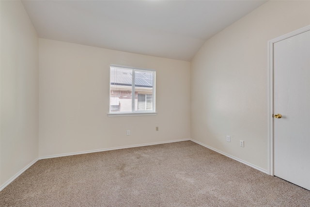 carpeted spare room with lofted ceiling