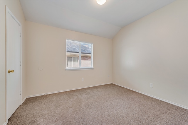 carpeted spare room with vaulted ceiling