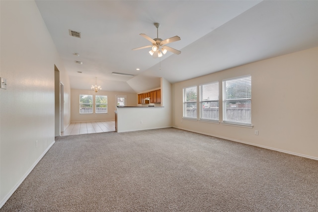 unfurnished living room with lofted ceiling, ceiling fan with notable chandelier, light colored carpet, and a healthy amount of sunlight