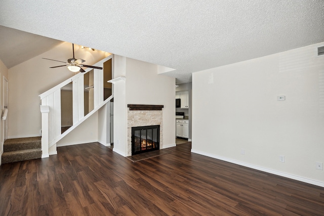 unfurnished living room with a textured ceiling, ceiling fan, dark hardwood / wood-style flooring, and a fireplace