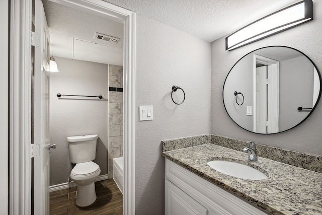 full bathroom featuring toilet, bathing tub / shower combination, wood-type flooring, vanity, and a textured ceiling