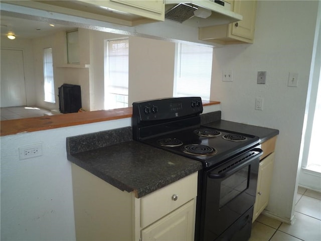 kitchen with range hood, light tile patterned floors, a wealth of natural light, and black range with electric stovetop