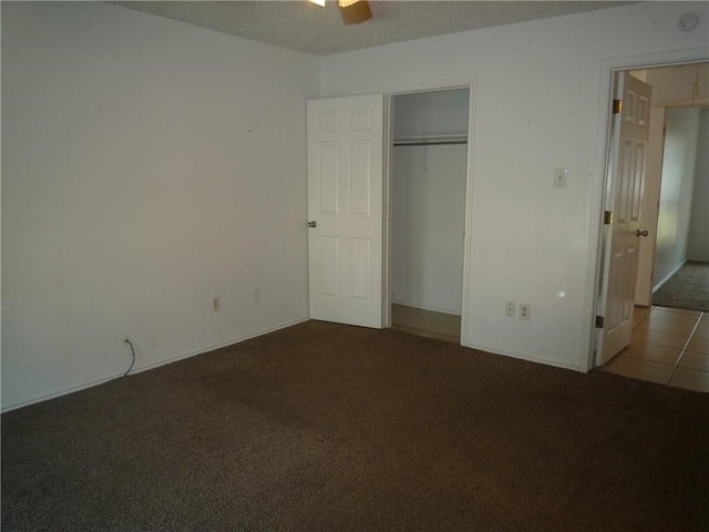 unfurnished bedroom featuring dark carpet, ceiling fan, and a closet