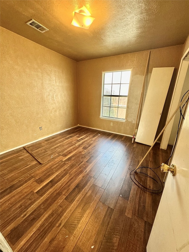 unfurnished bedroom featuring dark hardwood / wood-style flooring and a textured ceiling