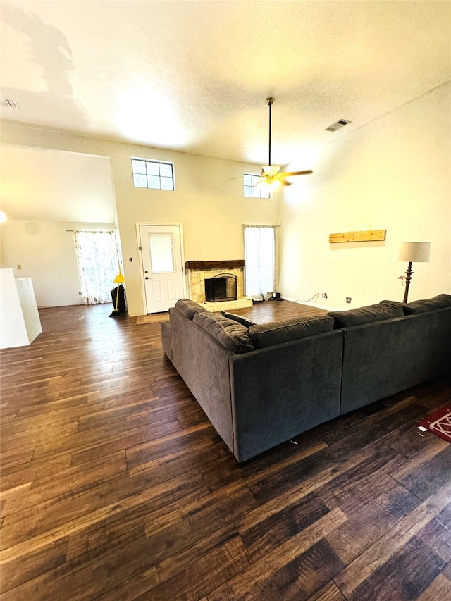 living room with a textured ceiling, a wealth of natural light, ceiling fan, and dark hardwood / wood-style floors