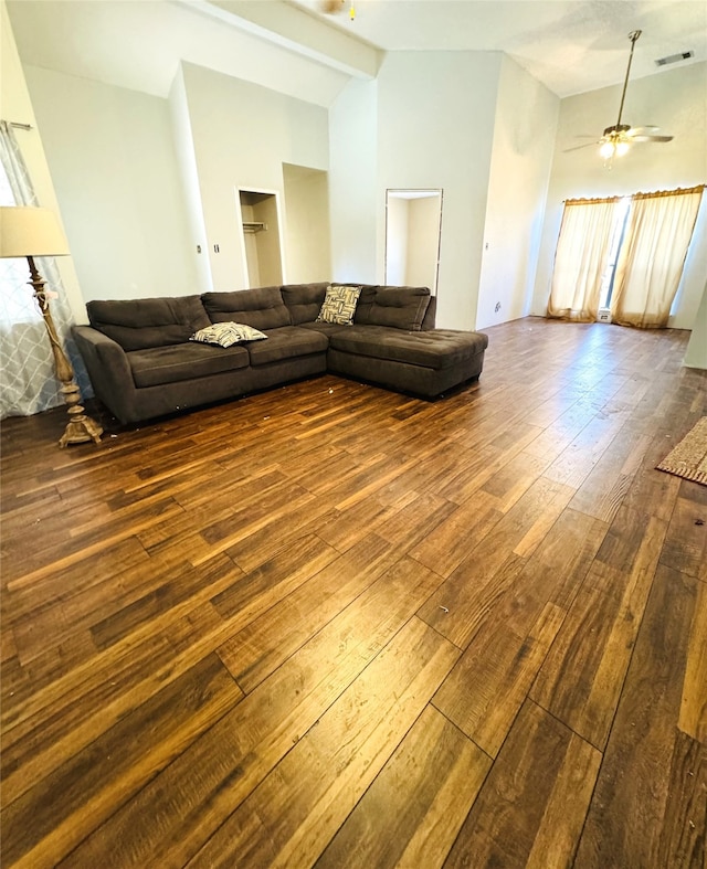 unfurnished living room featuring ceiling fan, wood-type flooring, and vaulted ceiling with beams