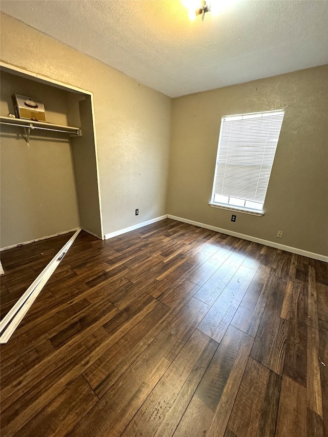 unfurnished bedroom featuring a closet, a textured ceiling, and dark hardwood / wood-style floors