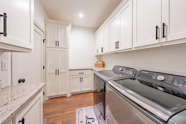 washroom featuring cabinets, light hardwood / wood-style flooring, and independent washer and dryer