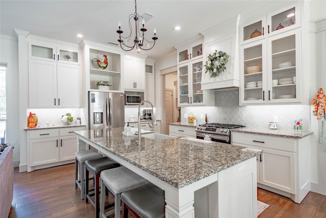 kitchen with tasteful backsplash, stainless steel appliances, an island with sink, and white cabinetry