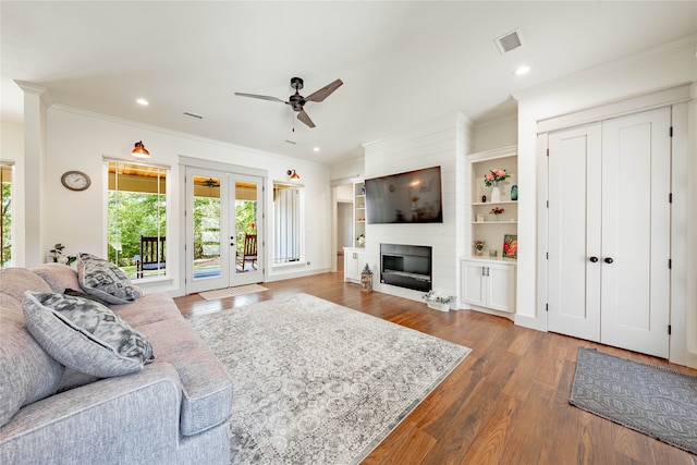 living room featuring dark hardwood / wood-style floors, ornamental molding, french doors, a fireplace, and ceiling fan