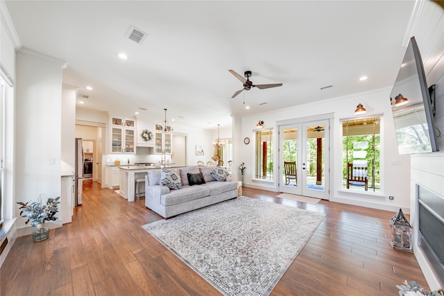 living room with ornamental molding, french doors, ceiling fan with notable chandelier, and hardwood / wood-style flooring