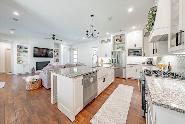 kitchen featuring ceiling fan with notable chandelier, white cabinets, appliances with stainless steel finishes, and a kitchen island with sink