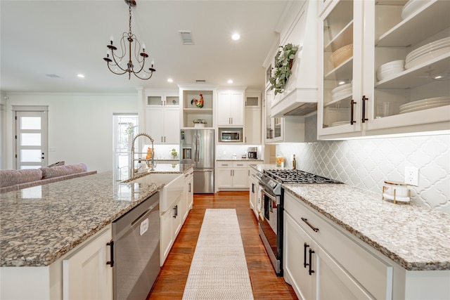 kitchen with stainless steel appliances, hanging light fixtures, light stone countertops, sink, and white cabinetry